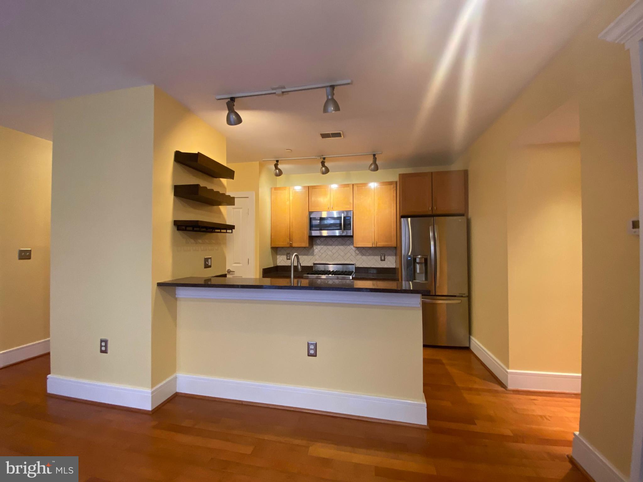 1654 Euclid Street Northwest, Unit 105 Washington, DC 20009 - Photo 10 of 29 a kitchen with stainless steel appliances wooden floor and a refrigerator