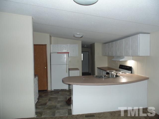 4522 Thomas Road Henderson, NC 27537 - Photo 12 of 19 a kitchen with kitchen island a counter top a stove and a refrigerator