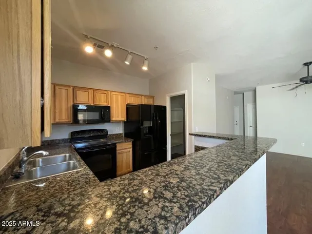 a kitchen with stainless steel appliances kitchen island granite countertop a refrigerator and a sink