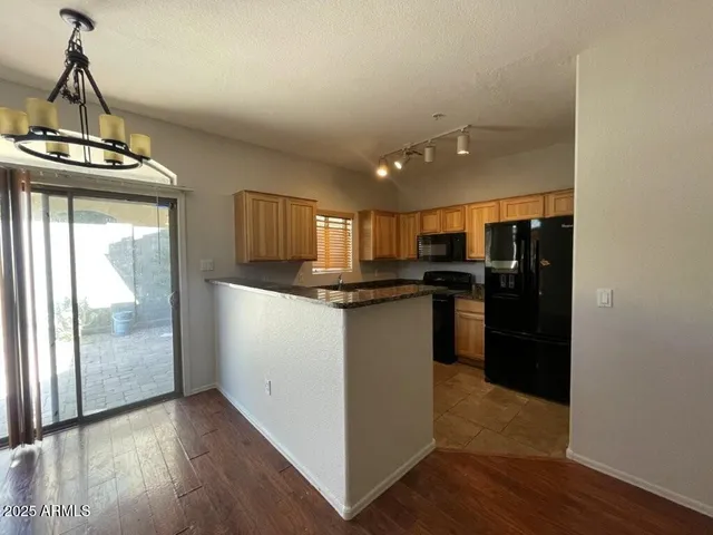 a kitchen with stainless steel appliances granite countertop a refrigerator a stove and a wooden floors