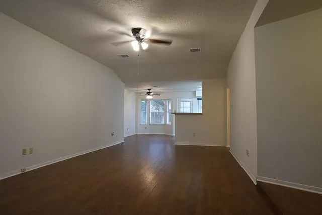 en empty room with windows and chandelier fan