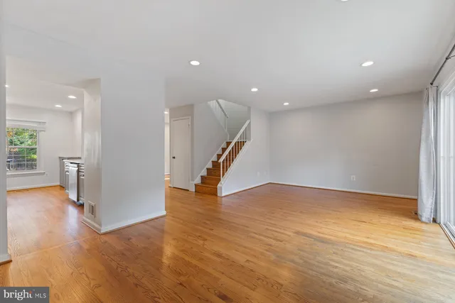 a view of an empty room with wooden floor and a chandelier