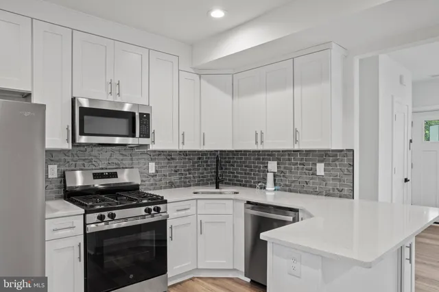 a kitchen with granite countertop white cabinets and stainless steel appliances