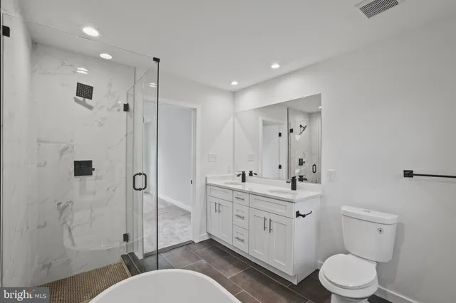 a bathroom with a toilet a sink a mirror a shower a vanity and window