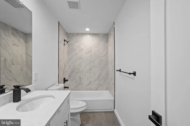 a bathroom with a granite countertop sink toilet and shower