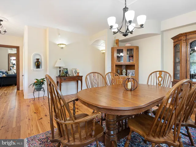 a dining room with wooden floor a chandelier a glass table and chairs