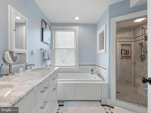 a spacious bathroom with a tub sink and mirror