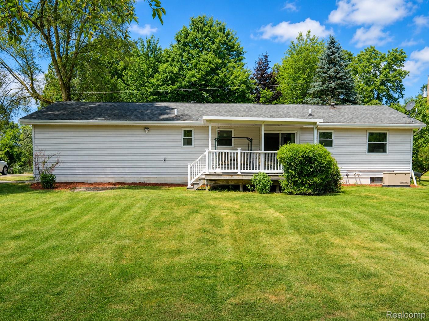 11399 Markley Road Gaines, MI 48436 - Photo 12 of 19 Expansive backyard featuring a manicured lawn, a covered deck with white railings, and siding exterior