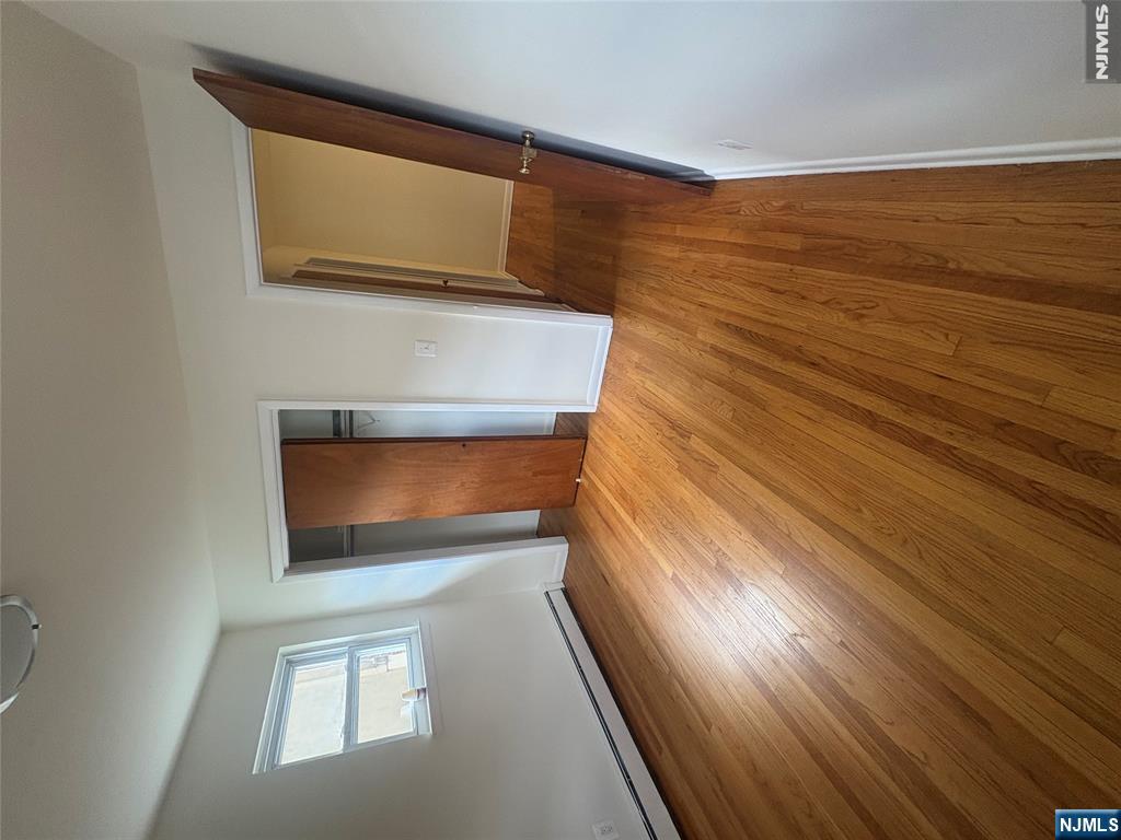 399 Walker Street, Unit 1B Fairview, NJ 07022 - Photo 6 of 11 a view of an empty room with wooden floor and a window