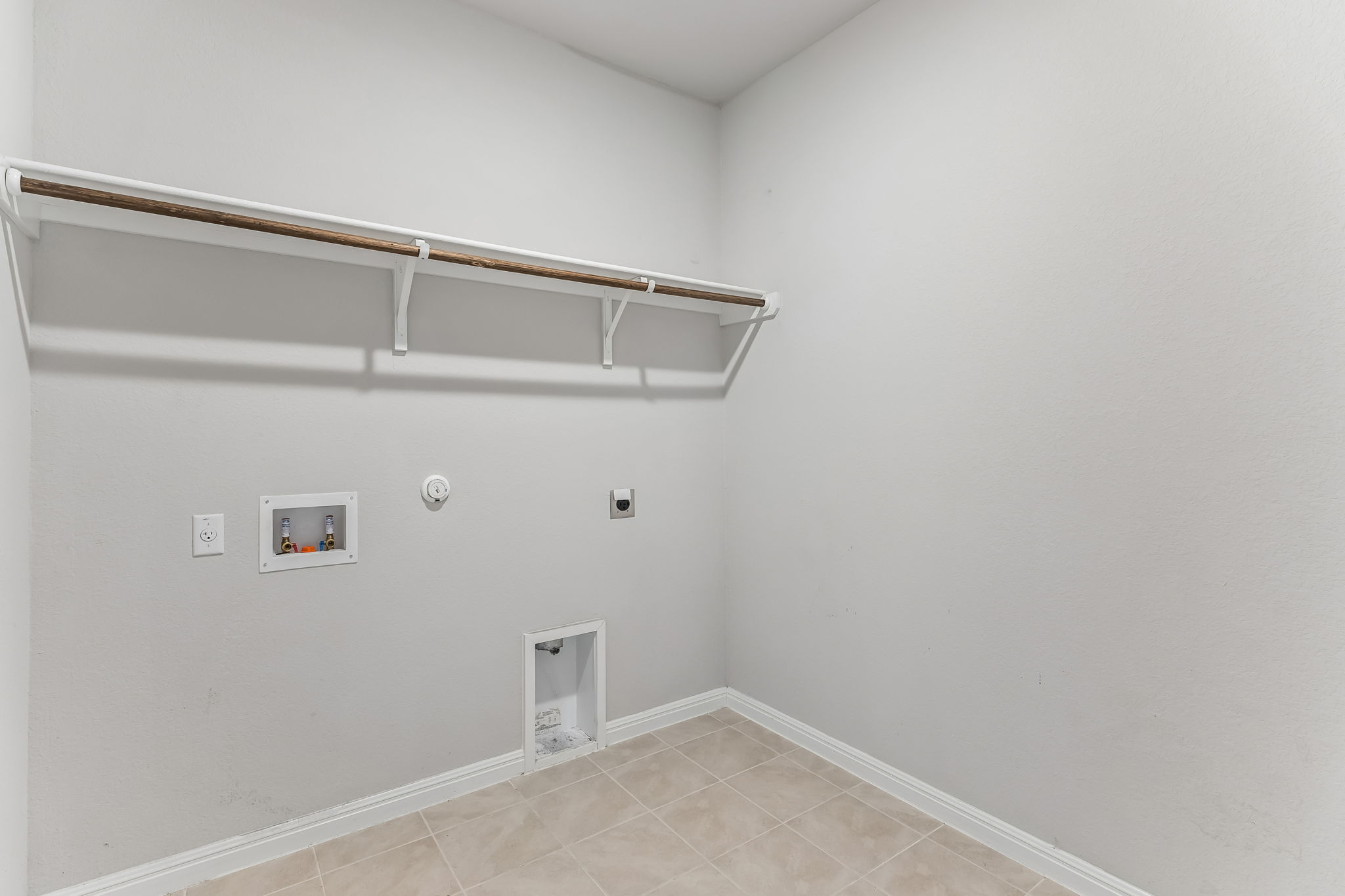 4009 Milano River Road Hutto, TX 78634 - Photo 15 of 40 A dedicated utility space features tile flooring and a sturdy overhead storage shelf.