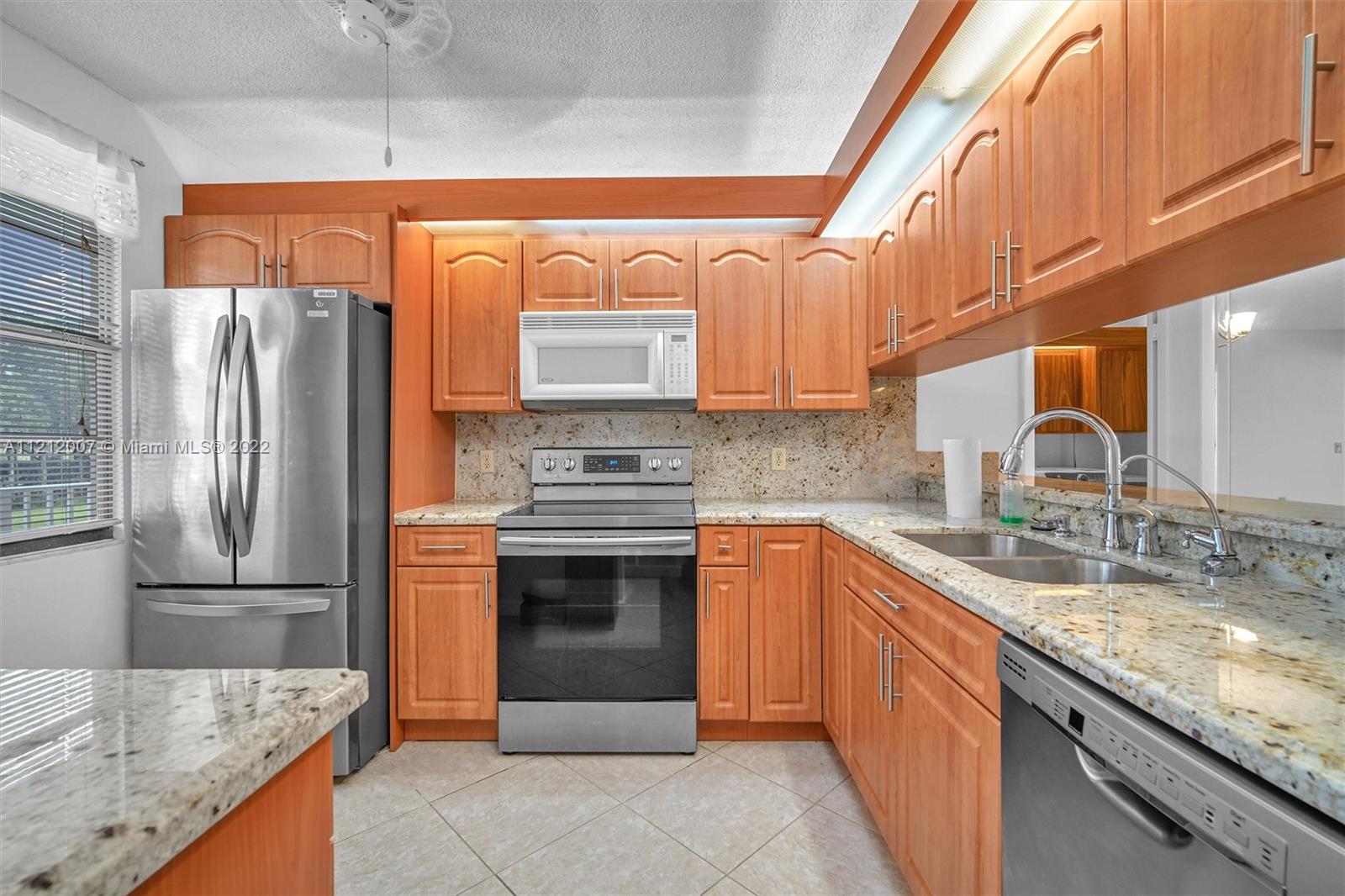 6025 Balboa Circle, Unit 202 Boca Raton, FL 33433 - Photo 7 of 28 a kitchen with stainless steel appliances granite countertop a sink stove and refrigerator
