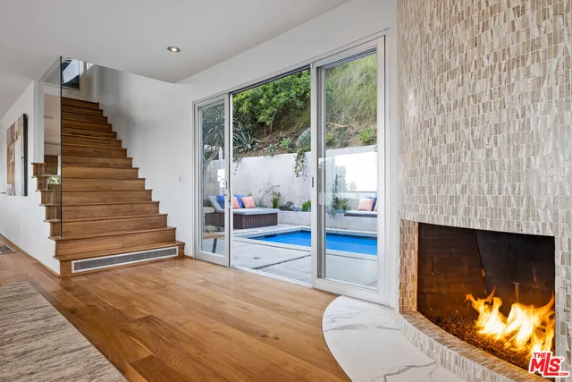 a view of an empty room with wooden floor and fireplace
