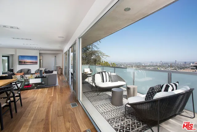 a living room with furniture a rug potted plant and a large window