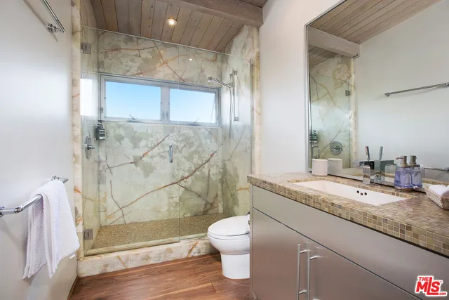 a bathroom with a granite countertop sink toilet a mirror and shower