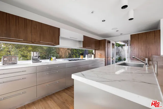 a view of a kitchen with kitchen island a sink wooden floor and a large window