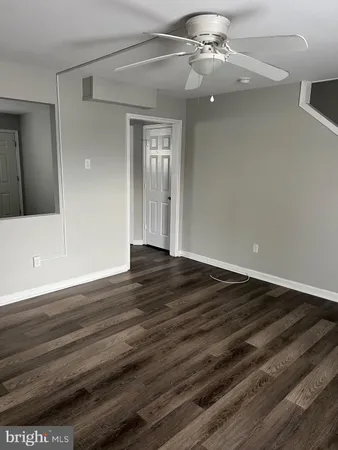 an empty room with wooden floor chandelier fan and windows