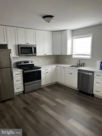 a kitchen with cabinets appliances and a wooden floor