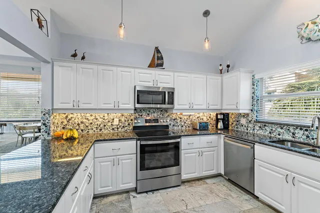 a kitchen with granite countertop a sink stainless steel appliances and white cabinets
