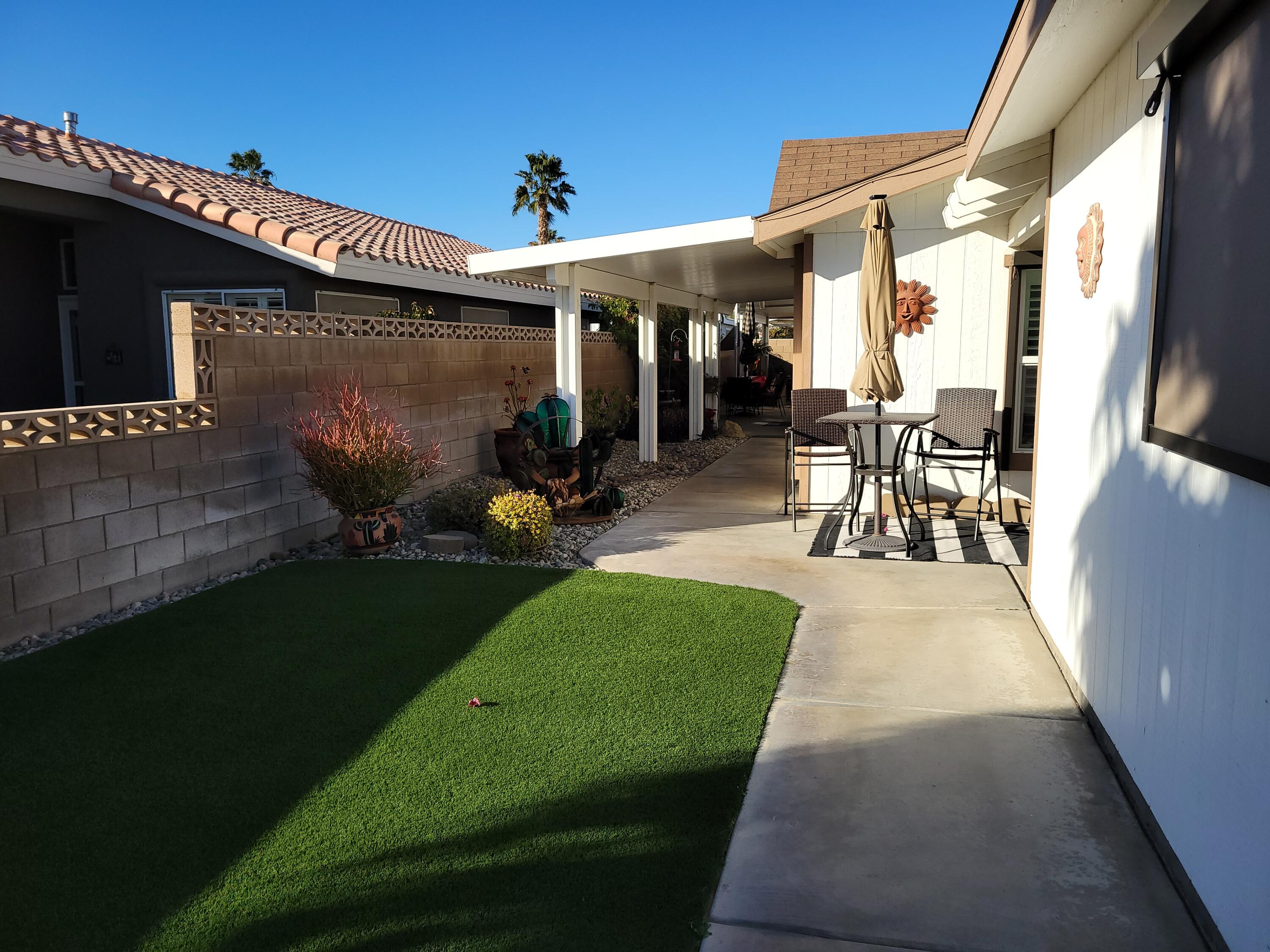 81641 Ave 48, Unit 56 Indio, CA 92201 - Photo 20 of 28 a view of a patio with table and chairs potted plants with wooden floor