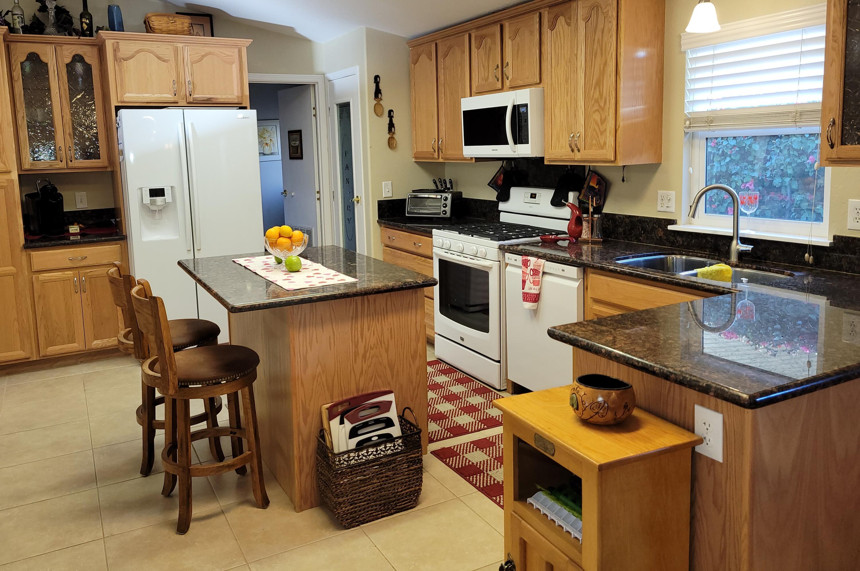 81641 Ave 48, Unit 56 Indio, CA 92201 - Photo 3 of 28 a kitchen with stainless steel appliances kitchen island granite countertop a sink a stove and refrigerator