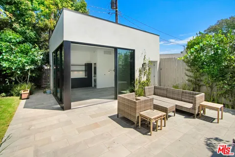 a patio with a table and chairs and potted plants