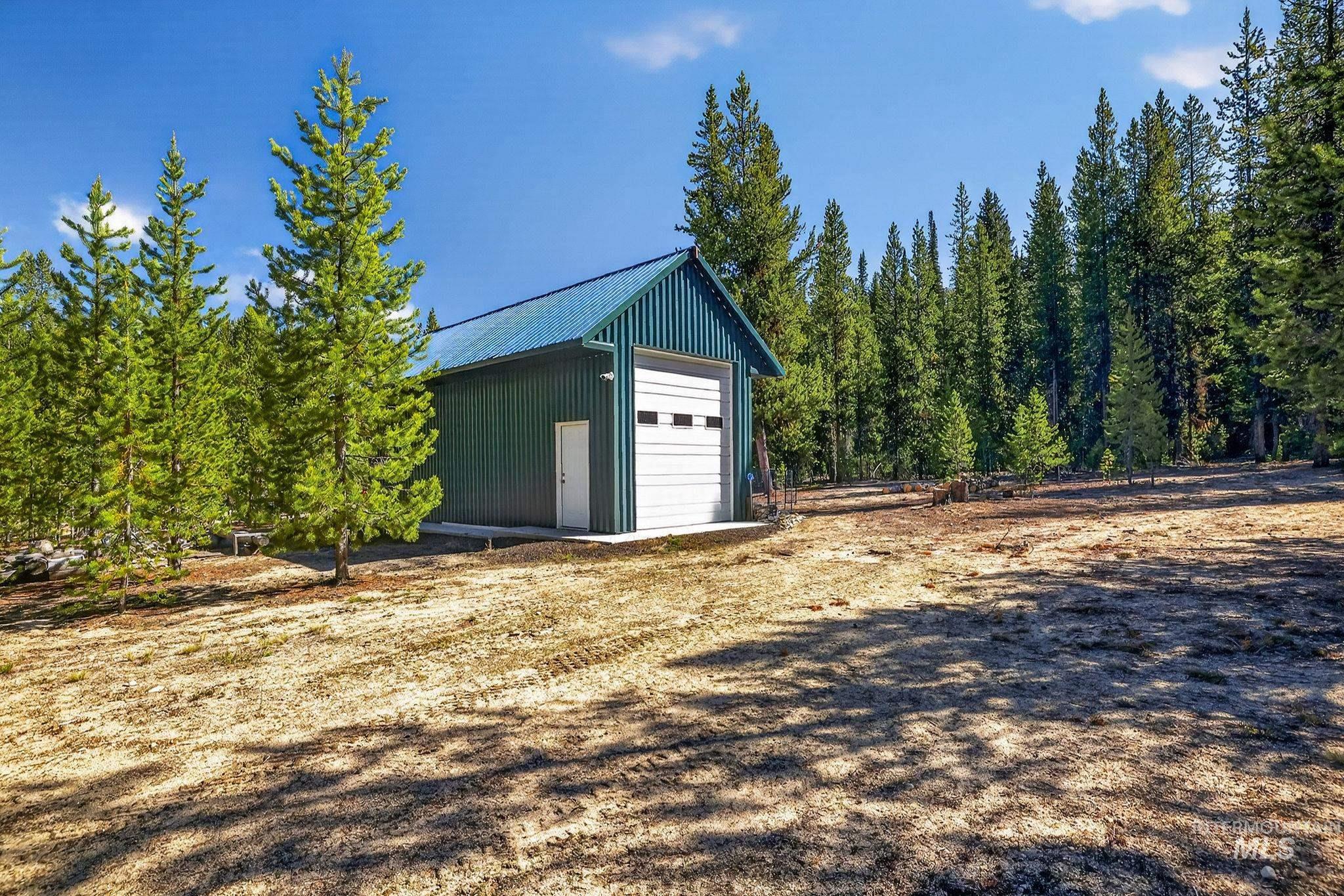 321 Secesh River Road McCall, ID 83638 - Photo 30 of 50 Metal outbuilding with a roll-up garage door and an entry door, featuring a blue metal roof and green siding