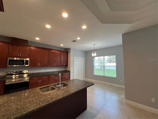 a kitchen with kitchen island granite countertop a stove sink and cabinets