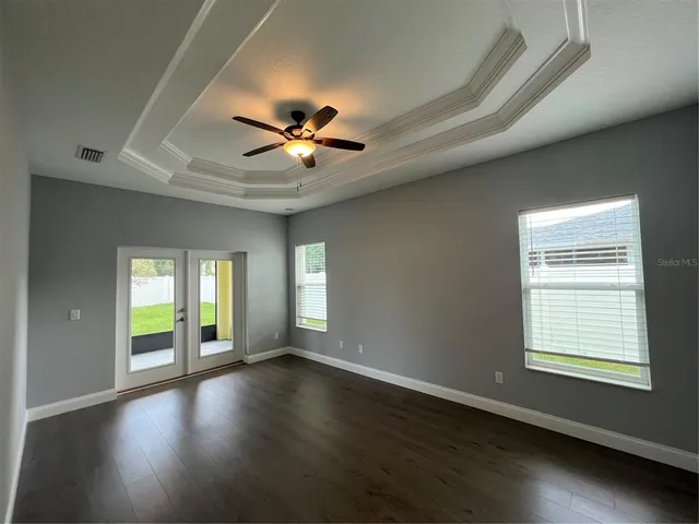 a view of an empty room with a window and wooden floor