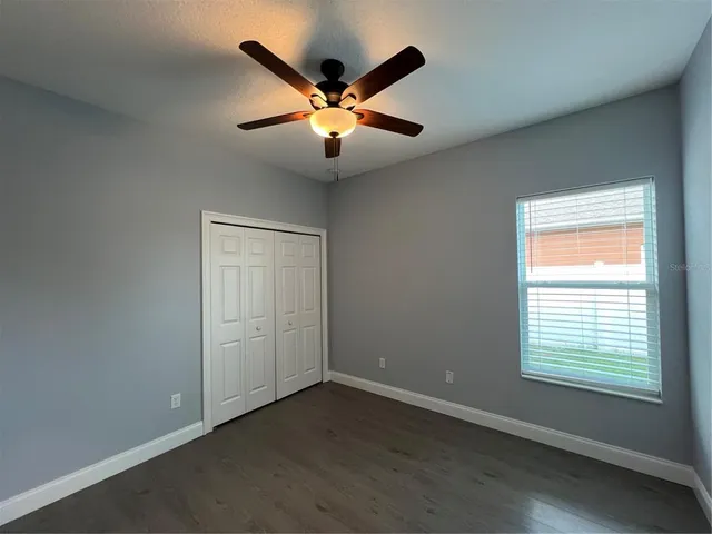 an empty room with wooden floor fan and windows