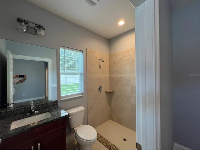 a bathroom with a granite countertop sink toilet a mirror a vanity and shower