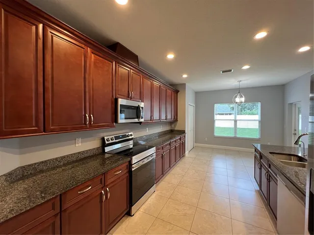 a kitchen with stainless steel appliances granite countertop wooden cabinets a stove top oven a sink and dishwasher