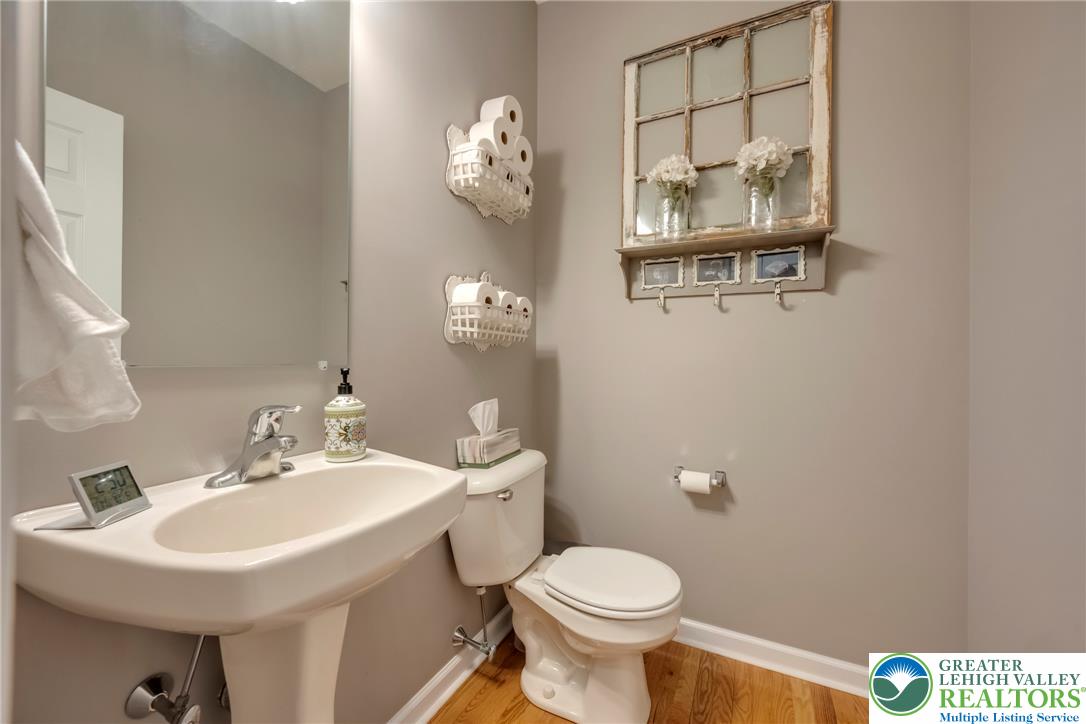 204 Bushkill Ridge Road Wind Gap, PA 18091 - Photo 19 of 48 A compact powder room with wood flooring and a classic pedestal sink, accented by a decorative wall shelf.