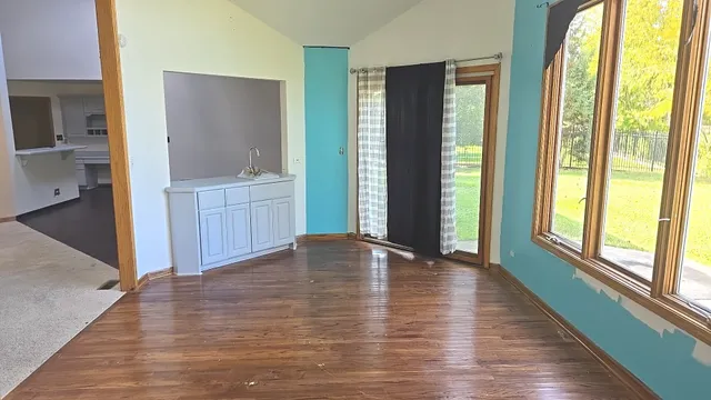 a view of an empty room with window and wooden floor
