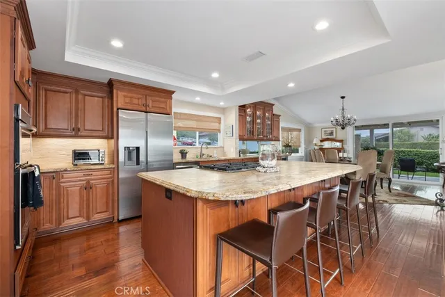 a kitchen with stainless steel appliances granite countertop a kitchen island a stove a sink a refrigerator and chairs