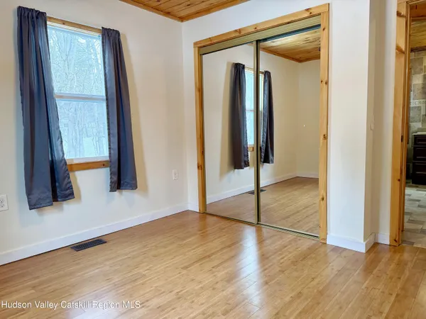 a view of empty room with wooden floor and fan