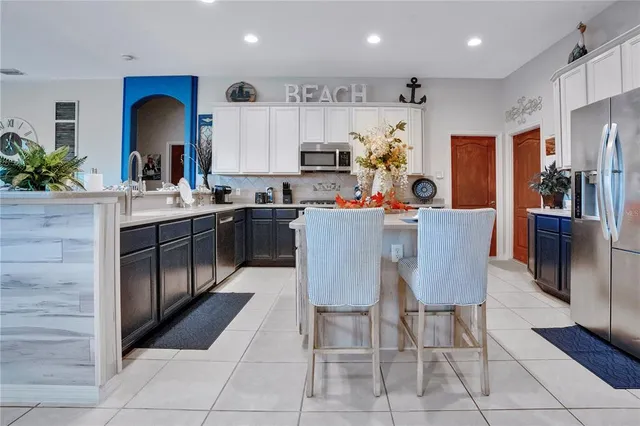 a kitchen with stainless steel appliances kitchen island granite countertop a stove a sink a dining table and chairs in it