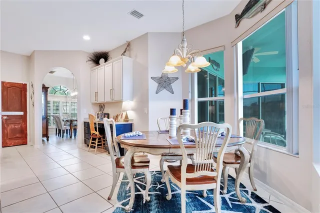 a dining room filled chandelier and kitchen view