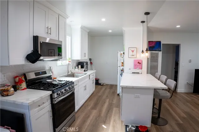 a kitchen that has a microwave a stove and wooden floor