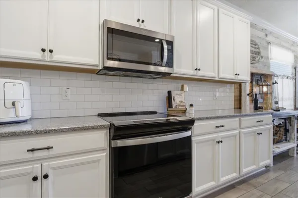 a kitchen with white cabinets and black appliances