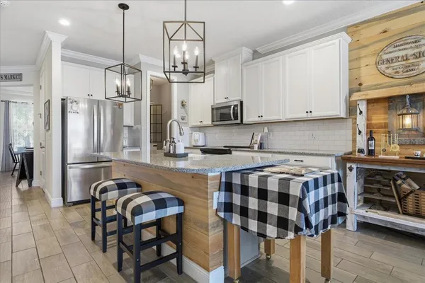 a kitchen with stainless steel appliances a table chairs in it and wooden floors