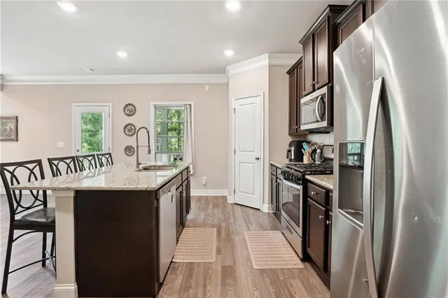 a kitchen with stainless steel appliances granite countertop a refrigerator a stove and a sink