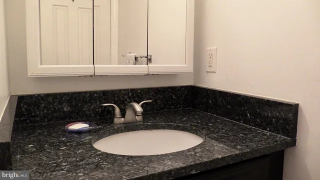 a bathroom with a granite countertop sink a mirror and vanity