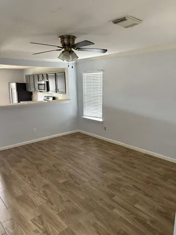 a view of a livingroom with a fireplace a ceiling fan and wooden floor