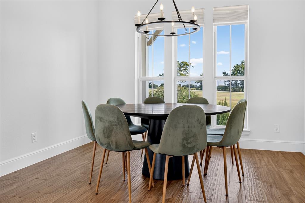 11032 Gregory Road Sanger, TX 76266 - Photo 22 of 40 Sophisticated dining room featuring a round black table, upholstered chairs with wood legs, and hardwood flooring throughout