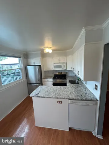 a kitchen with stainless steel appliances granite countertop a sink a stove a refrigerator and a granite counter tops with wooden floors