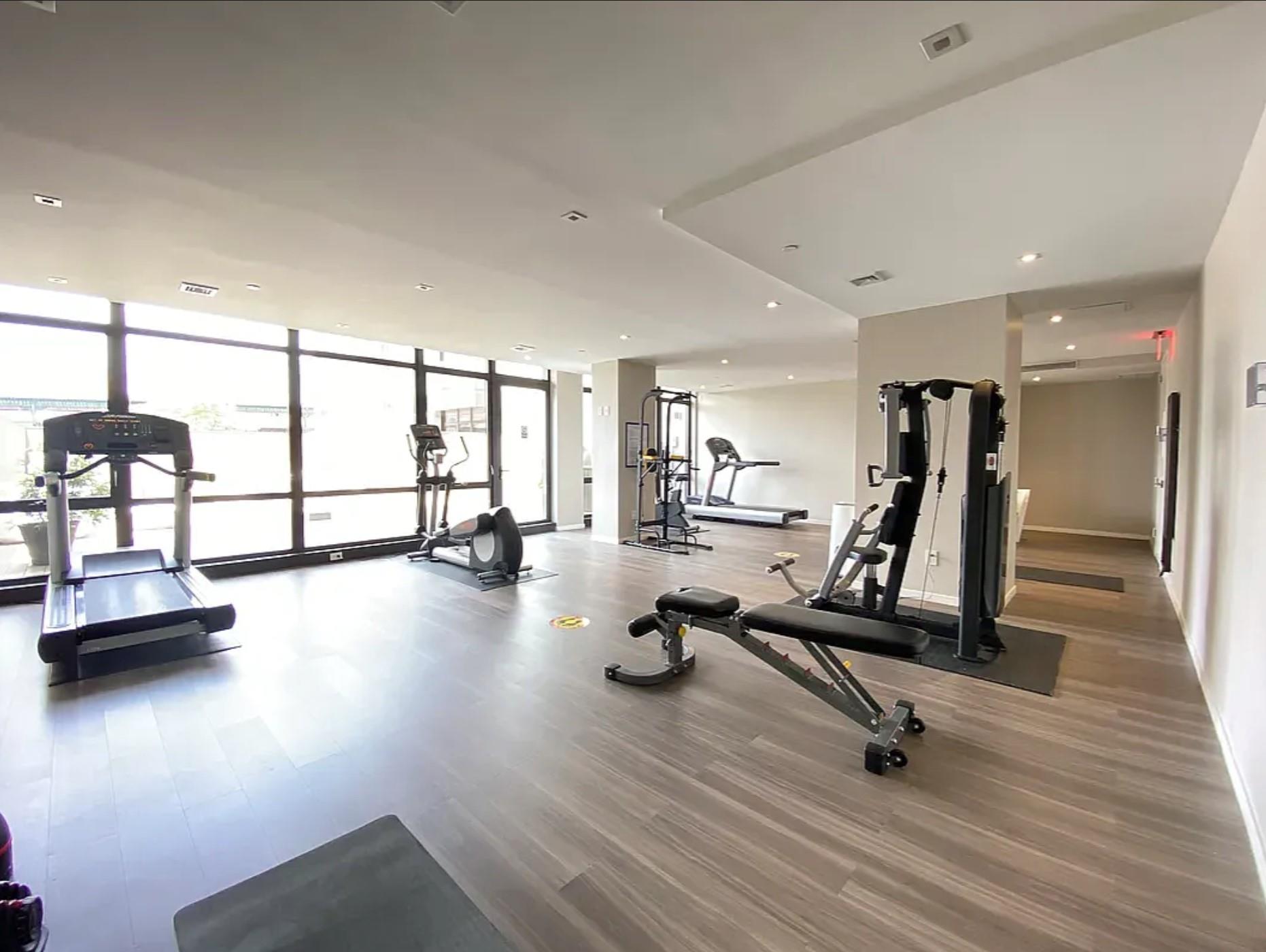 24-12 42nd Road, Unit 3E Queens, NY 11101 - Photo 12 of 13 Exercise room featuring expansive windows, wood finished floors, and recessed lighting