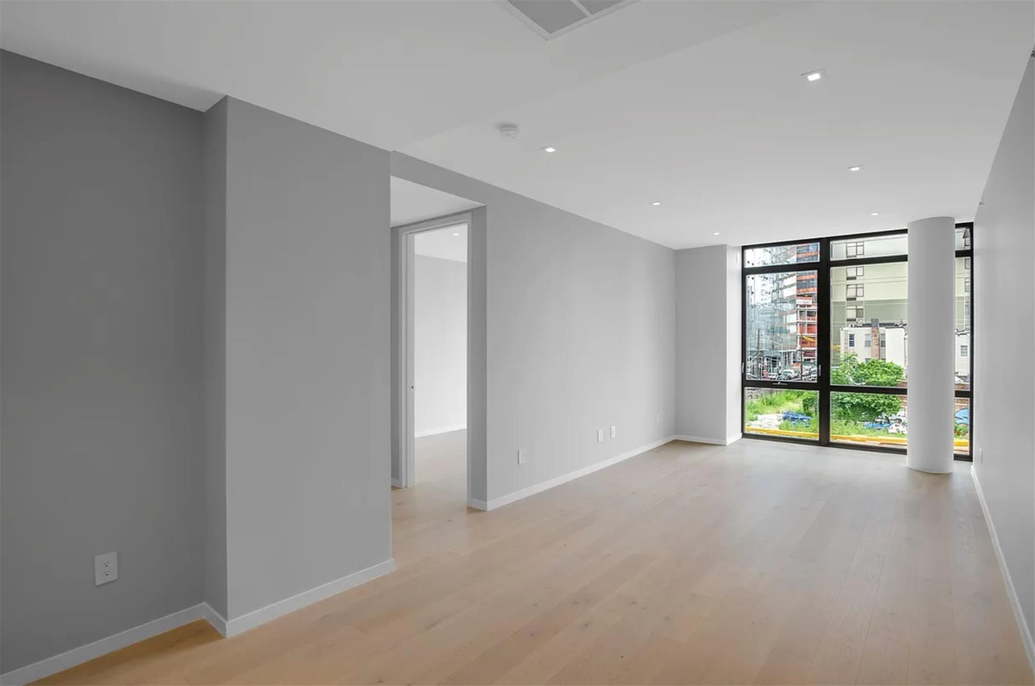 24-12 42nd Road, Unit 3E Queens, NY 11101 - Photo 2 of 13 Unfurnished room featuring floor to ceiling windows, light wood-type flooring, and recessed lighting