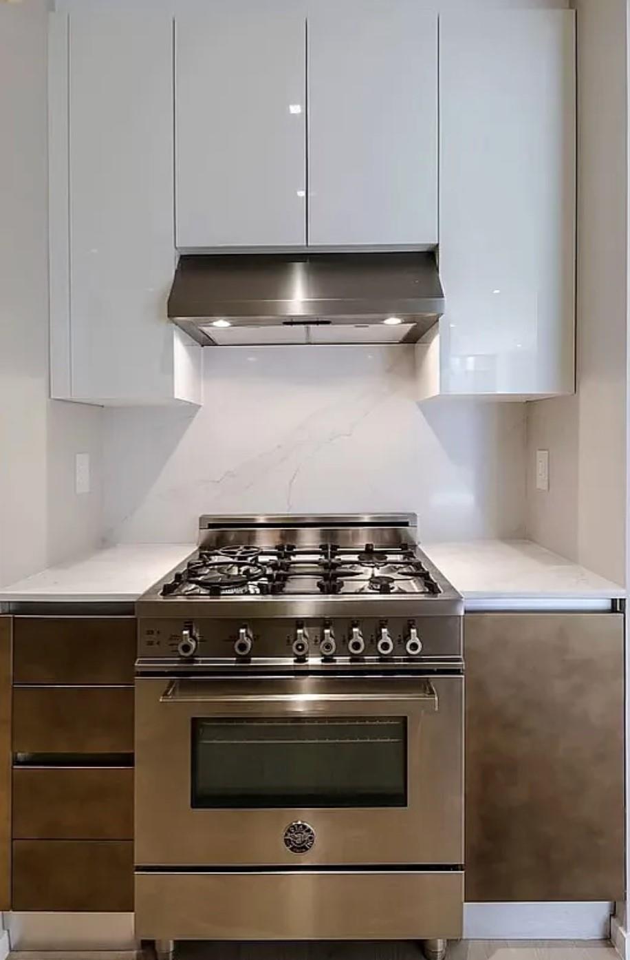 24-12 42nd Road, Unit 3E Queens, NY 11101 - Photo 8 of 13 Kitchen with modern cabinets, high end stainless steel range oven, white cabinets, range hood, and light countertops