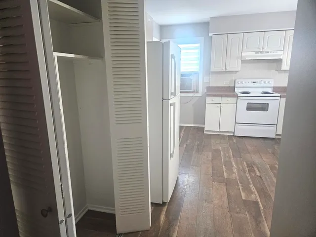 a white refrigerator freezer sitting inside of a kitchen with stainless steel appliances wooden floor