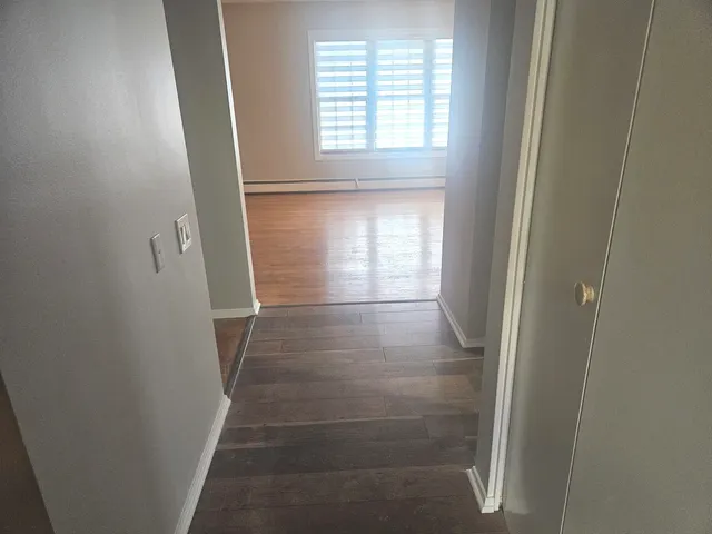 a view of an empty room with a window and wooden floor